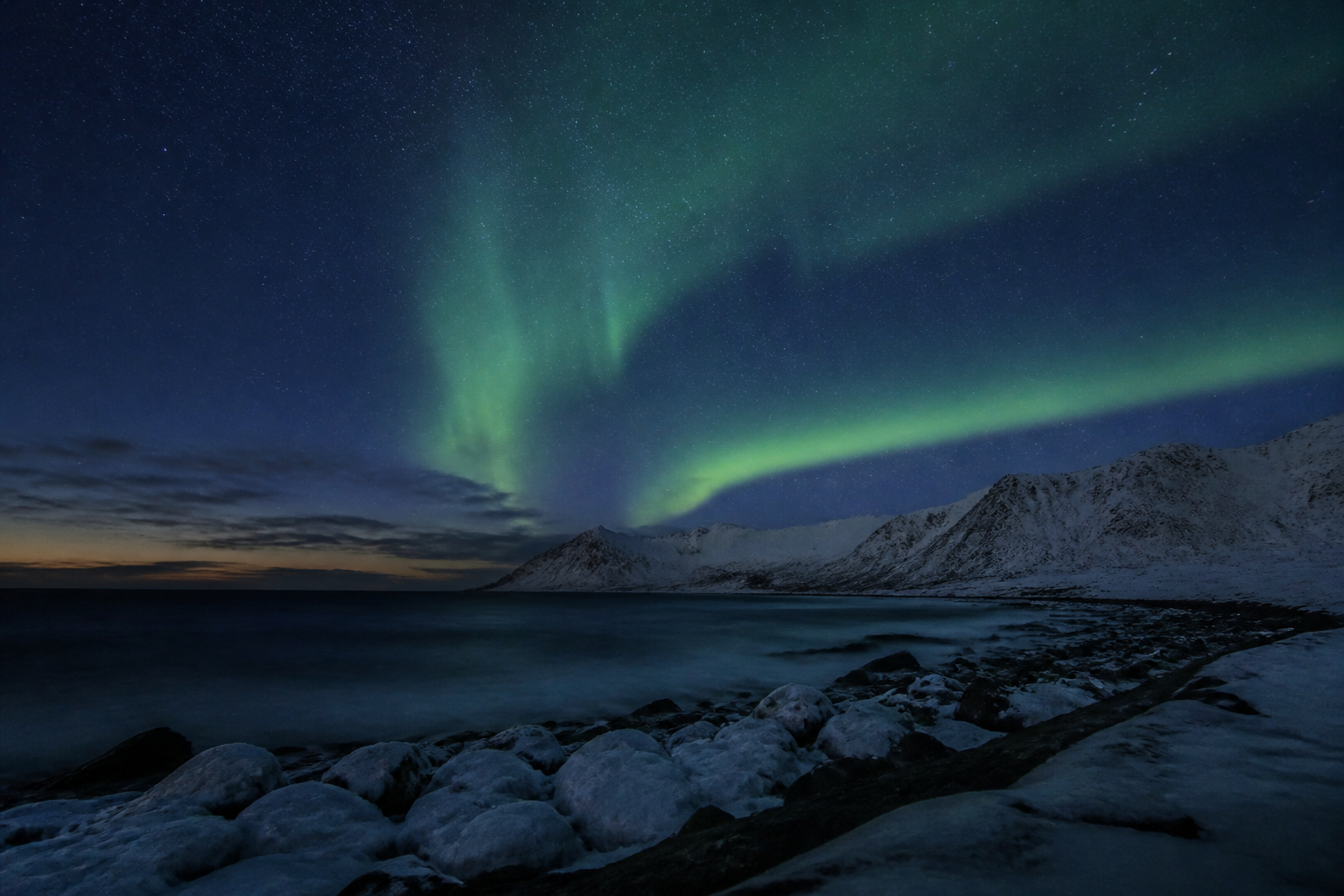 Northern Lights above a snow-covered Arctic coast and mountains