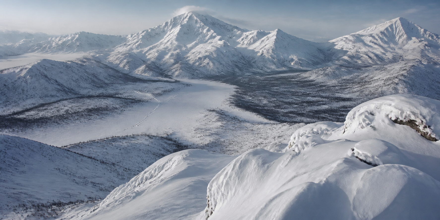 A vast snow-covered mountain wilderness in winter